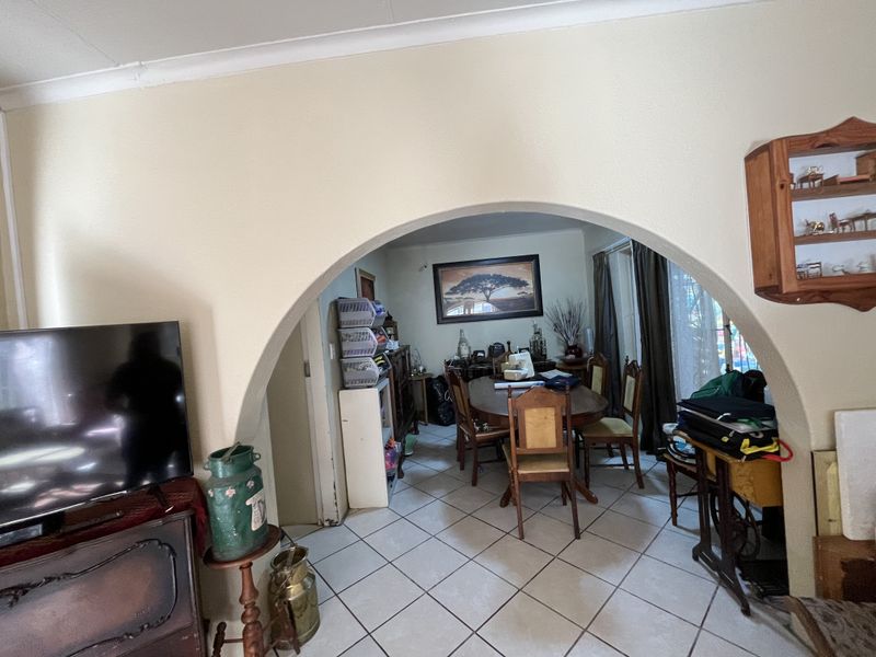 Open plan living and dining area featuring a prominent architectural archway and tiled flooring throughout.