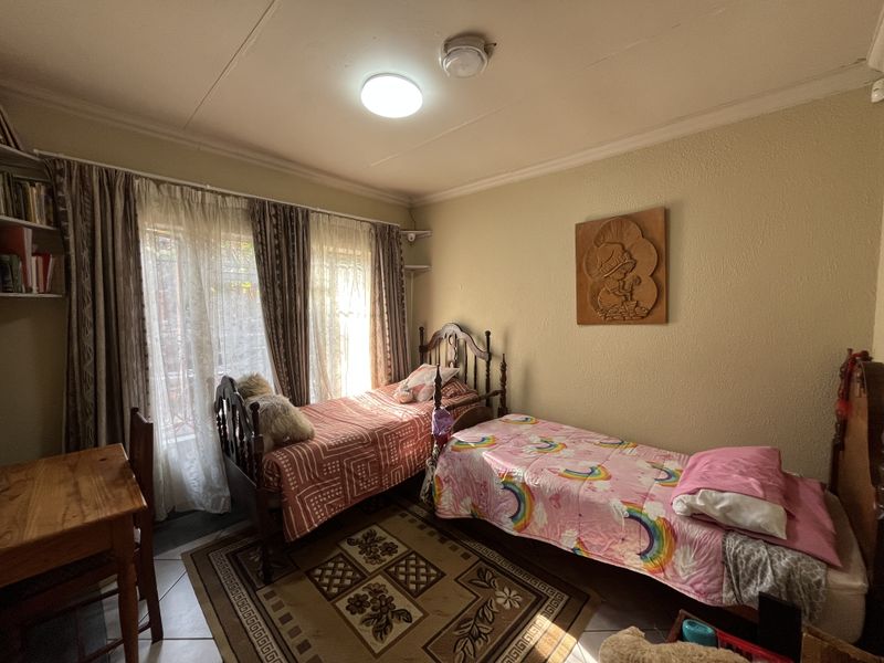 A functional bedroom featuring tiled flooring and a standard ceiling light fixture, providing a comfortable space with natural light from the window.