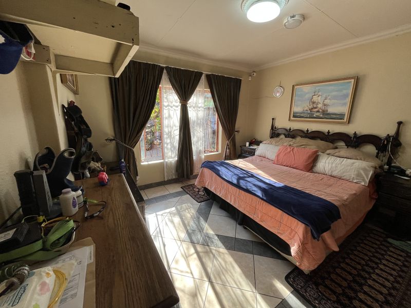 A bedroom featuring tiled flooring and natural light from a window, providing a functional space for rest.