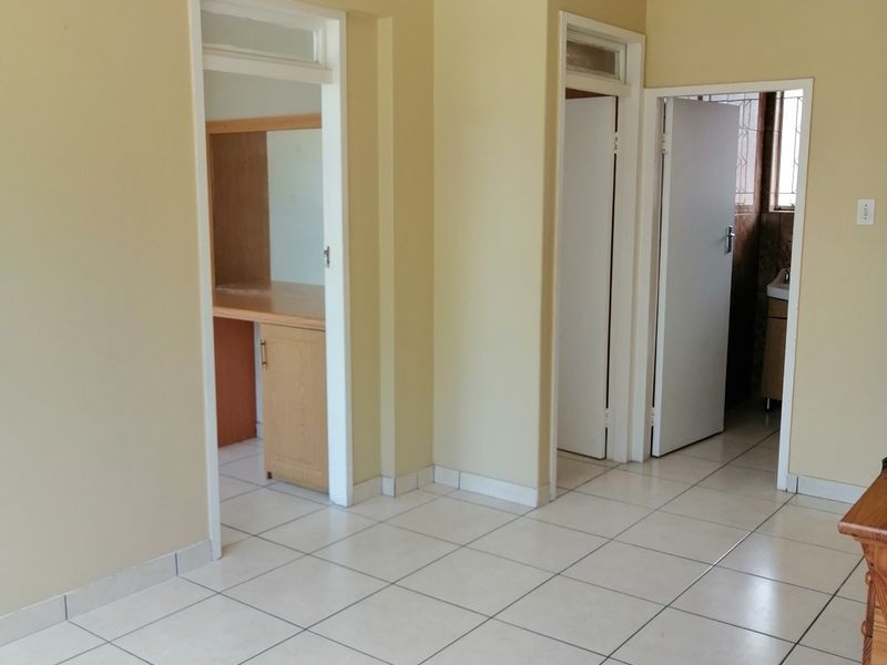 A bright, tiled hallway providing access to multiple rooms, featuring neutral wall tones and built-in storage cabinetry.