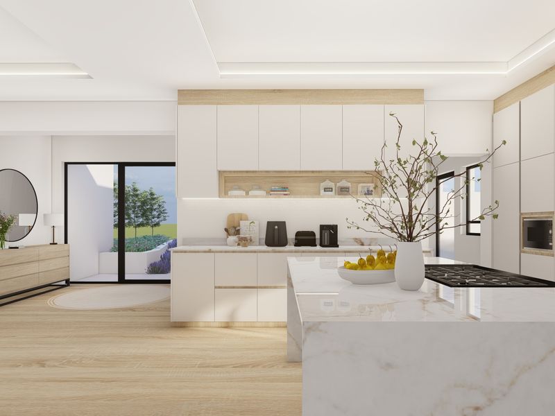 Modern open-plan kitchen featuring sleek white cabinetry, a marble-topped island with integrated cooktop, and seamless access to the outdoor patio area.