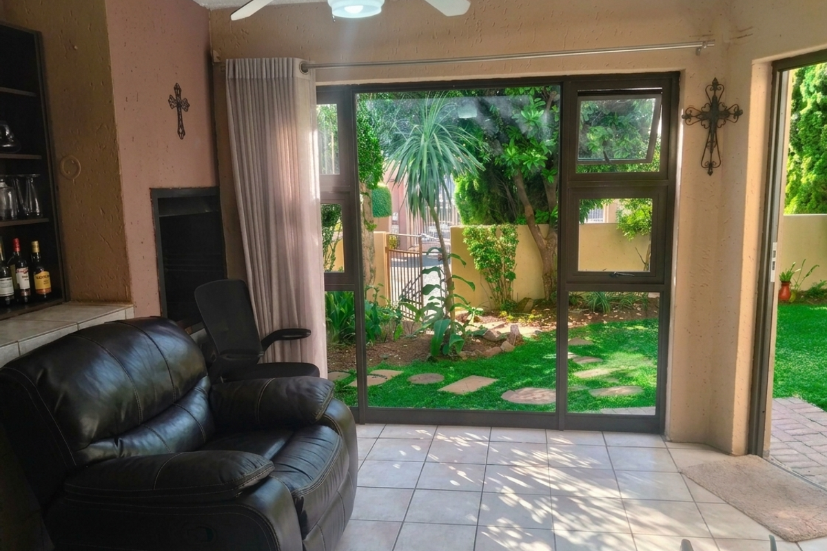 A living room featuring a built-in fireplace, tiled flooring, and large sliding glass doors that provide direct access to the garden.