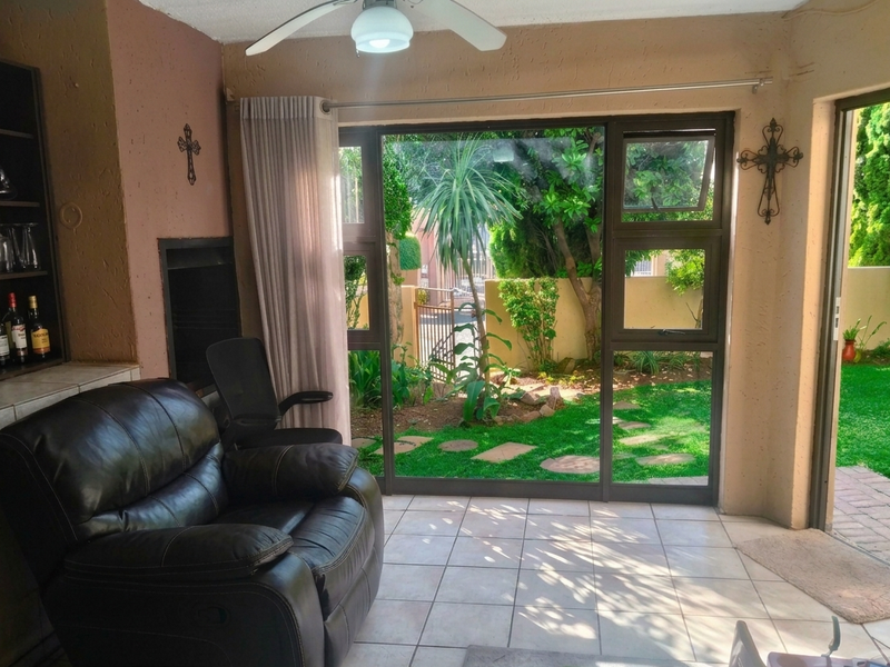 A living room featuring a built-in fireplace, tiled flooring, and large sliding glass doors that provide direct access to the garden.