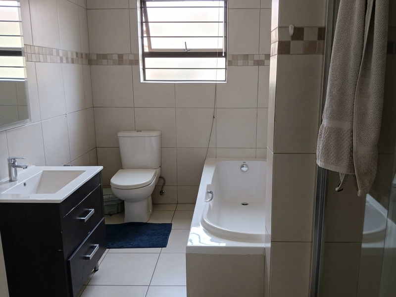 A functional bathroom featuring a modern vanity, a bathtub, a separate shower enclosure, and neutral wall and floor tiling.