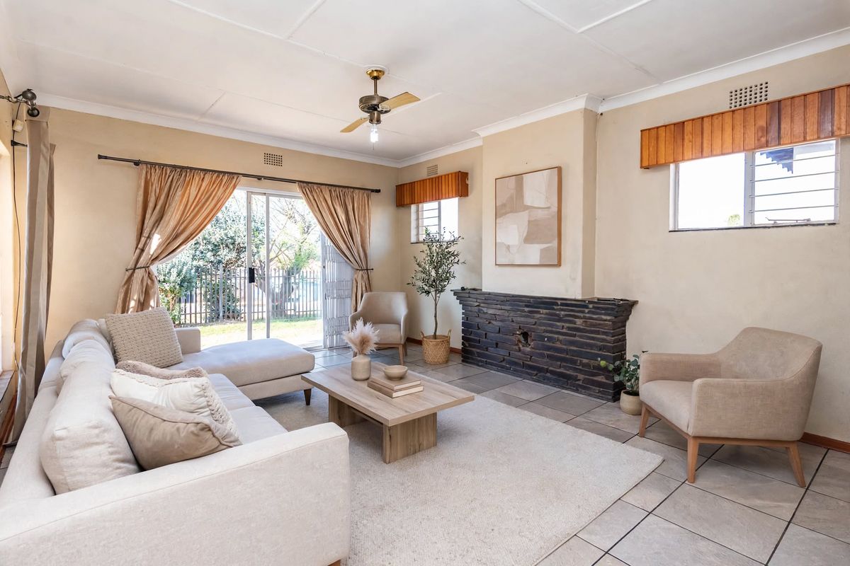 Spacious living room featuring a brick fireplace, tiled flooring, and sliding glass doors providing direct access to the garden.