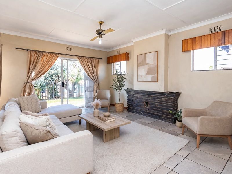 Spacious living room featuring a brick fireplace, tiled flooring, and sliding glass doors providing direct access to the garden.