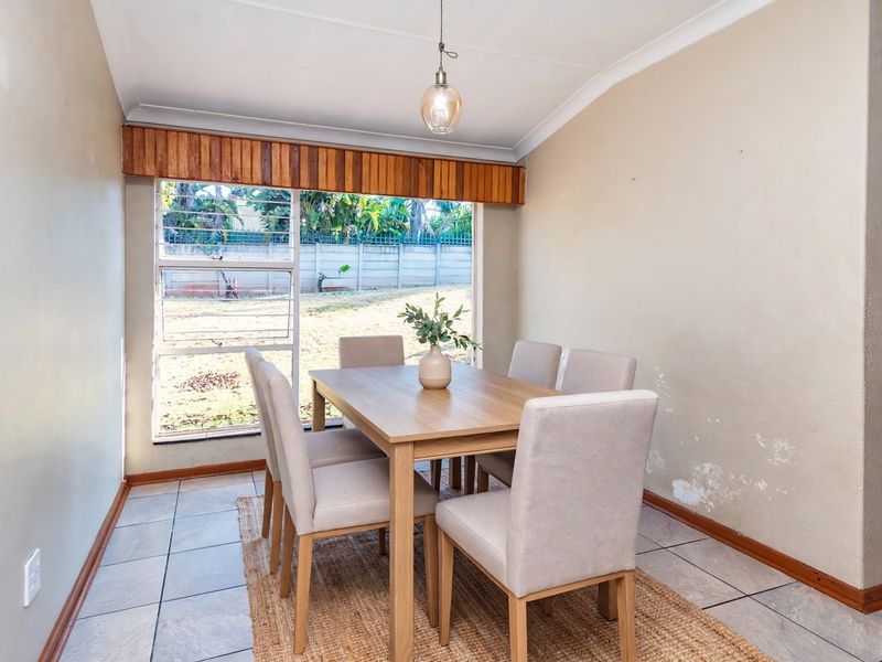 Dining area featuring tiled flooring, a louvered window with timber pelmet, and pendant lighting. Note visible wall dampness requiring attention.