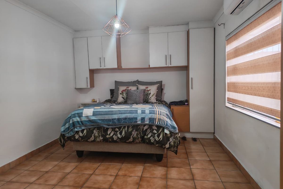 A bedroom featuring built-in cabinetry, tiled flooring, a split-system air conditioner, and modern pendant lighting.