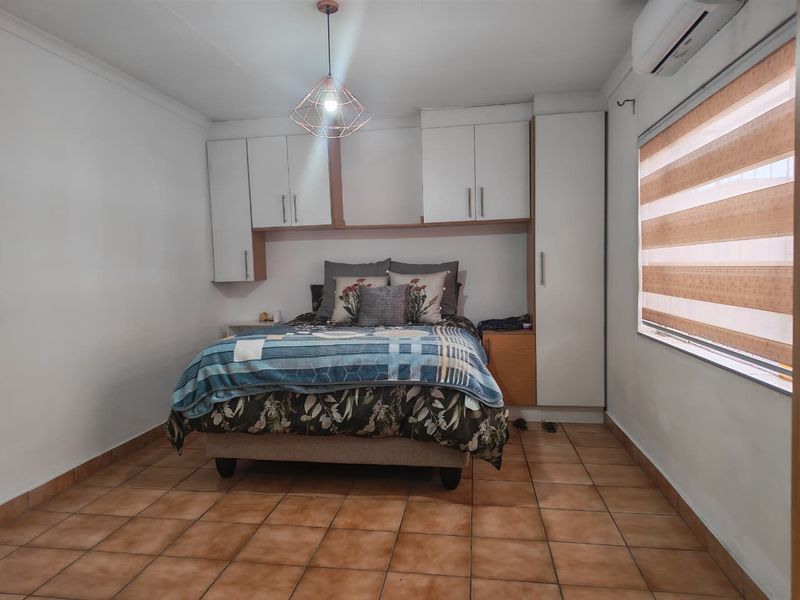 A bedroom featuring built-in cabinetry, tiled flooring, a split-system air conditioner, and modern pendant lighting.