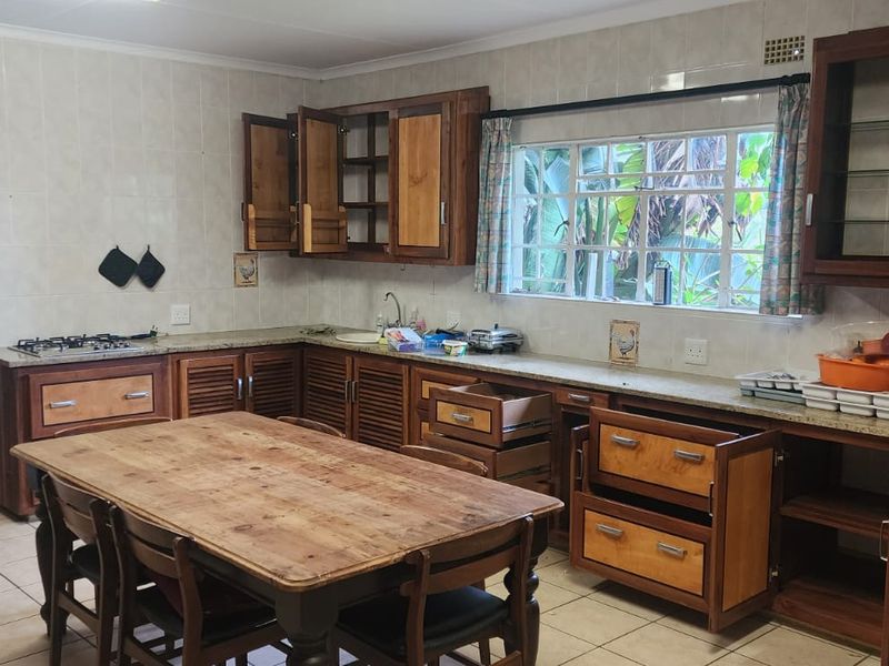 A dated kitchen featuring wooden cabinetry, granite countertops, and a gas hob, requiring cosmetic updates to modernize the space.