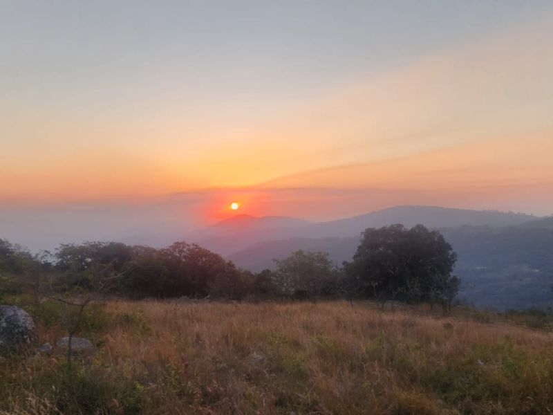 A scenic landscape view of the farm property featuring rolling hills and mountains at sunset.