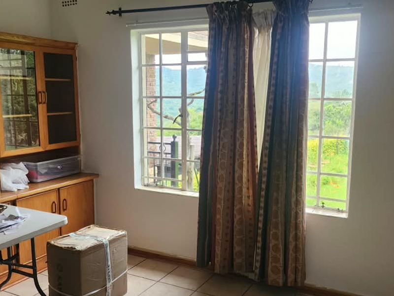 A bedroom featuring tiled flooring, built-in wooden cabinetry, and grid-pane windows with views of the surrounding landscape.