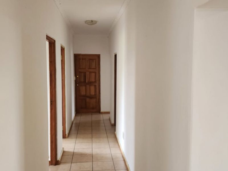 A functional hallway featuring tiled flooring and multiple wooden doors providing access to various rooms within the property.