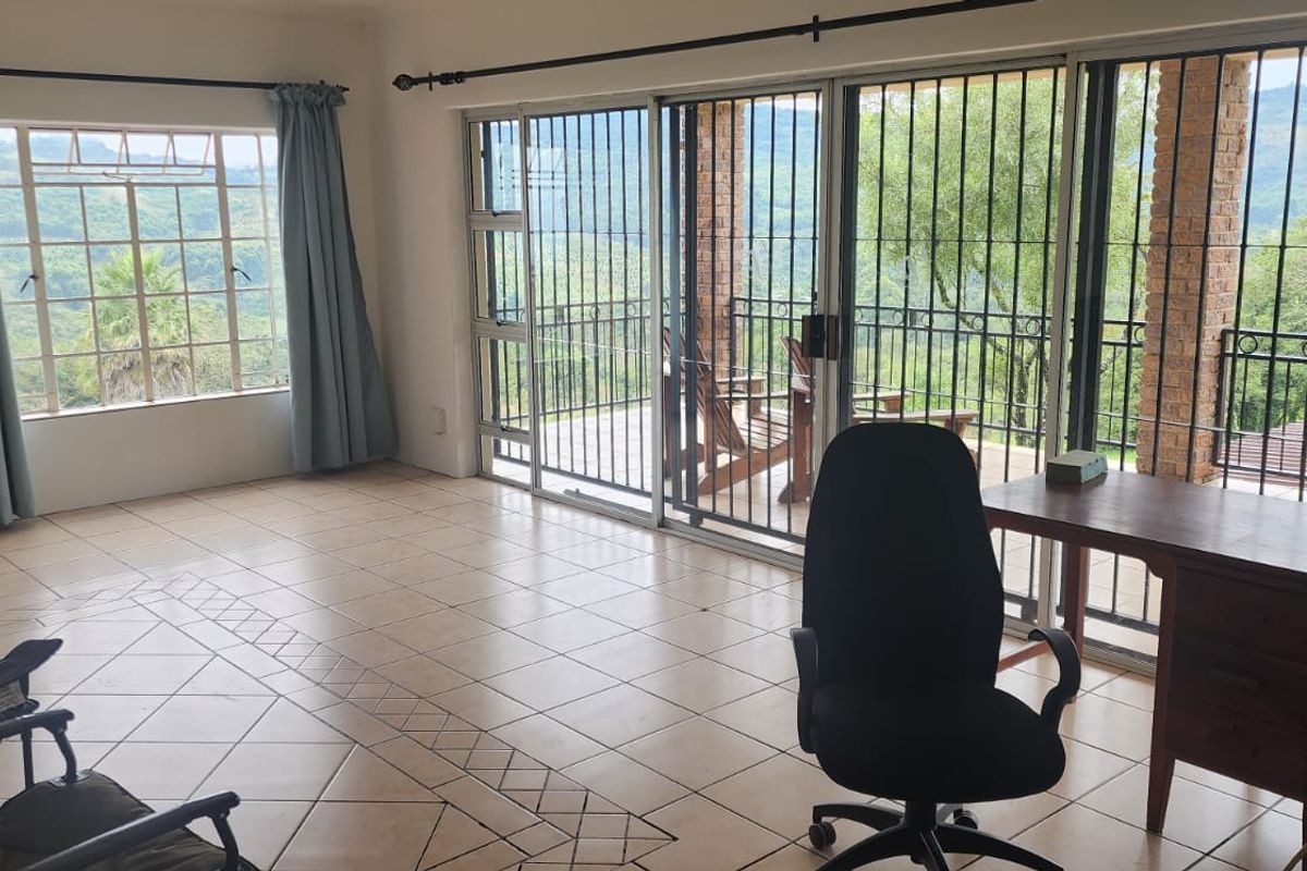 Spacious living area featuring ceramic tile flooring, large windows, and sliding glass doors that open to a scenic outdoor patio with security bars.