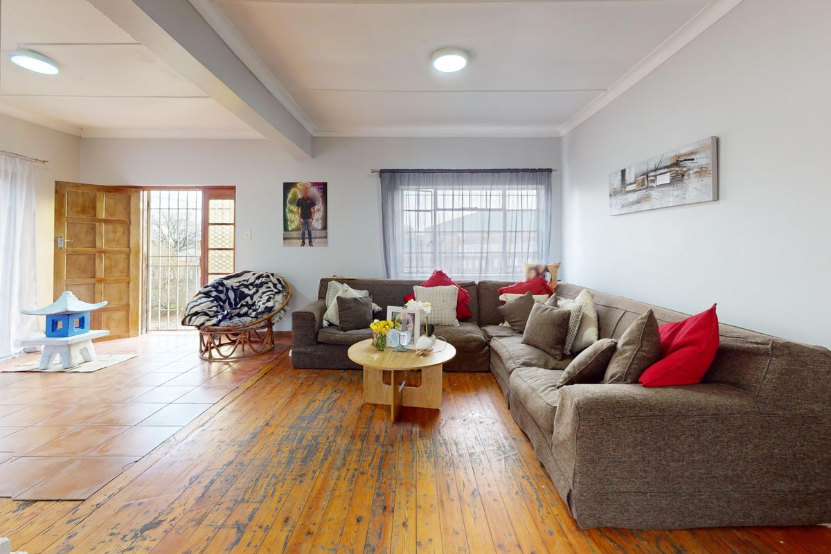 Spacious living area featuring a combination of timber and tiled flooring, with direct access to an outdoor area through a security gate.