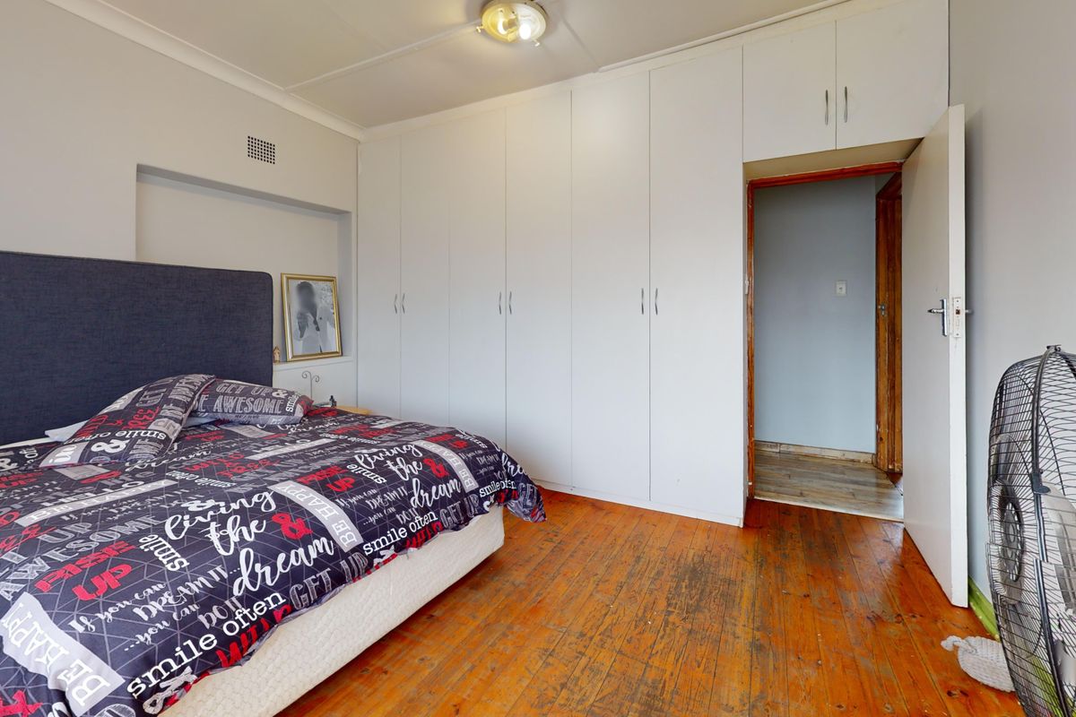 Bedroom featuring polished timber flooring and extensive built-in white cabinetry providing ample storage space.