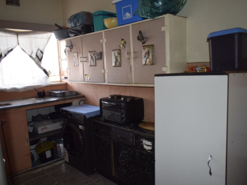 A dated kitchen featuring original cabinetry, tiled splashbacks, and a functional sink area, offering significant potential for modernization and renovation.