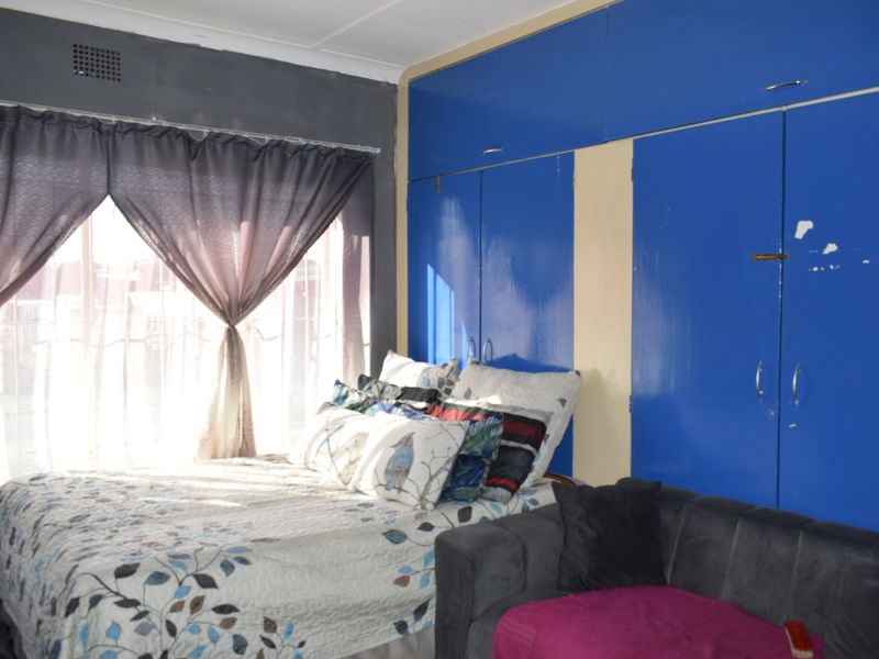 A bedroom featuring built-in cupboards with visible wear and peeling paint, requiring cosmetic updates to improve the overall aesthetic.