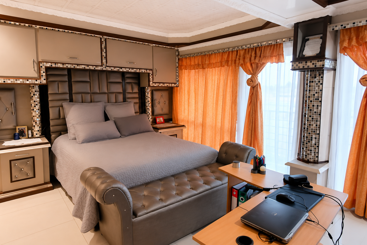 A well-maintained bedroom featuring extensive built-in cabinetry, a custom headboard with mosaic detailing, and large windows with integrated curtain pelmets.