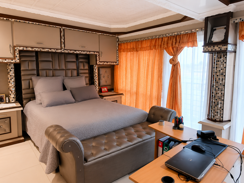 A well-maintained bedroom featuring extensive built-in cabinetry, a custom headboard with mosaic detailing, and large windows with integrated curtain pelmets.