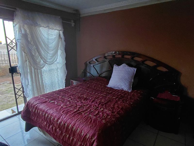 Bedroom featuring tiled flooring and a sliding glass door with security gate providing direct access to the exterior.
