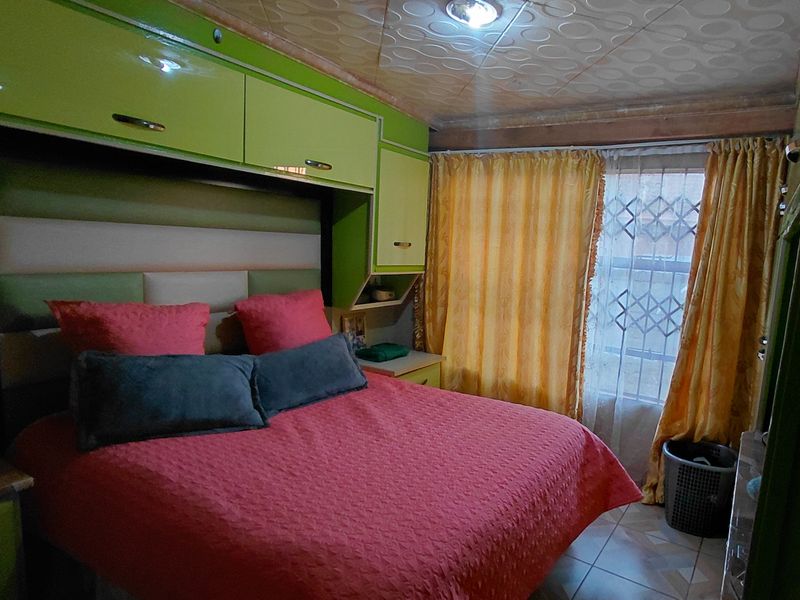 A bedroom featuring built-in cabinetry, tiled flooring, and a security gate on the window.