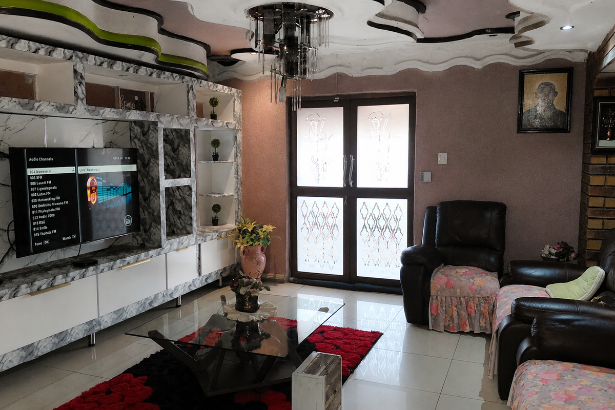 Living room featuring a large built-in marble-effect media wall, decorative ceiling detail, tiled floors, and glass-paneled double doors leading to the exterior.