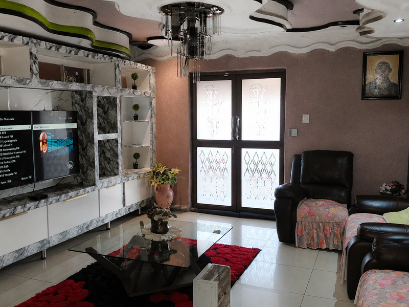 Living room featuring a large built-in marble-effect media wall, decorative ceiling detail, tiled floors, and glass-paneled double doors leading to the exterior.