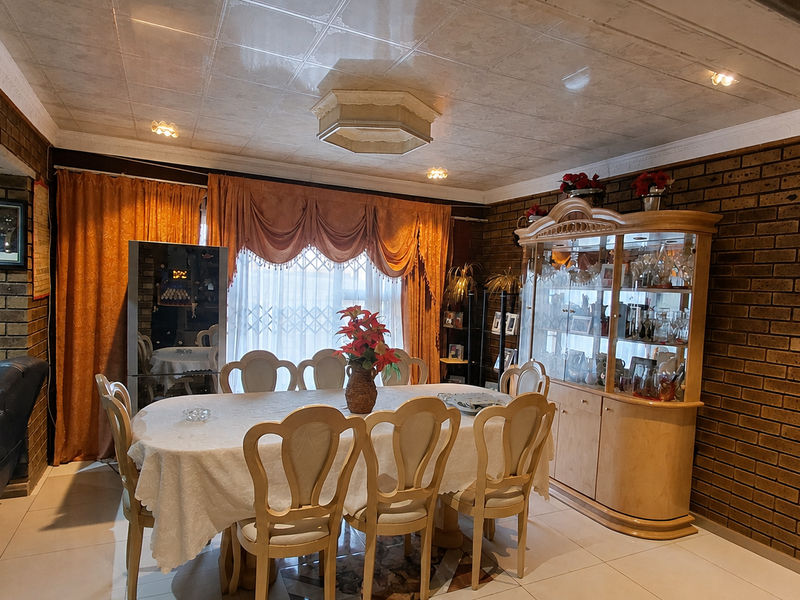 A traditional dining room featuring exposed brick walls, tiled ceiling, and a built-in display cabinet, offering a classic and structured layout.