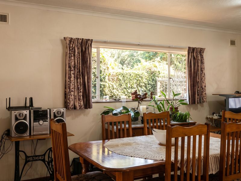 A functional dining room featuring a large sliding window that provides natural light and views of the garden.