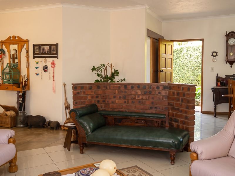Open plan living area featuring tiled flooring and a distinctive exposed brick partition wall, providing a clear transition between living and dining spaces.