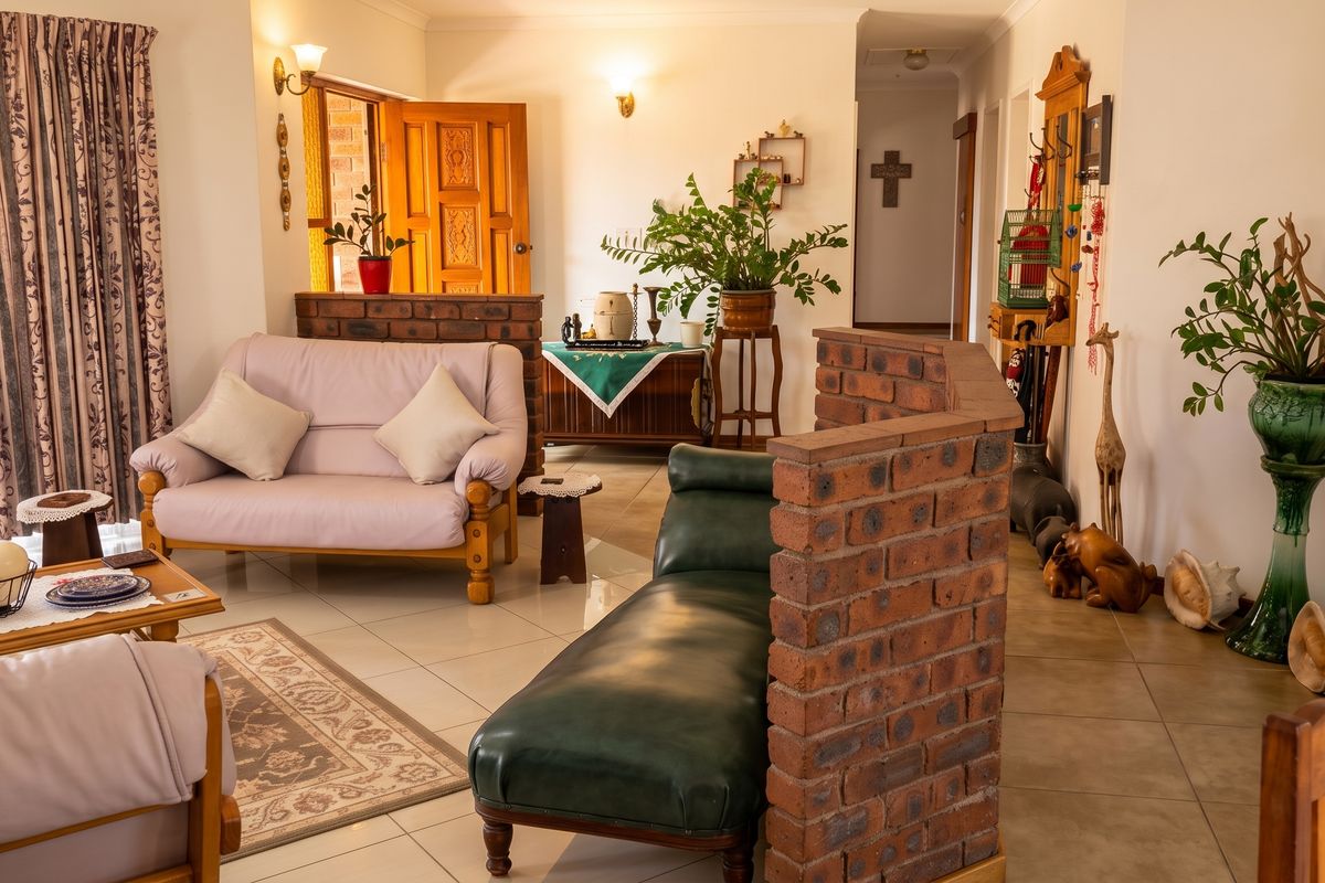 A living room featuring tiled flooring, a decorative brick partition wall, and access to an exterior entrance.