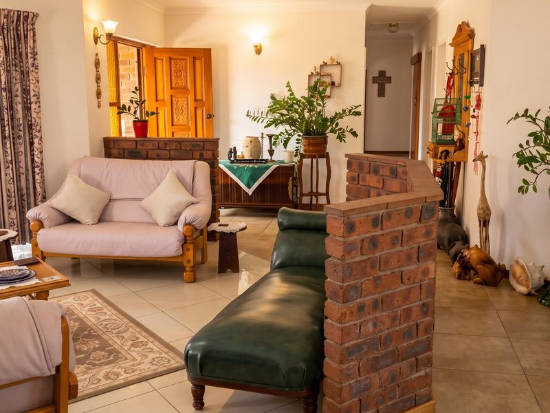 A living room featuring tiled flooring, a decorative brick partition wall, and access to an exterior entrance.
