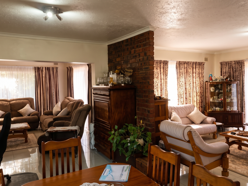 Spacious open-plan living area featuring an exposed brick partition wall, tiled flooring, and large windows with natural light.