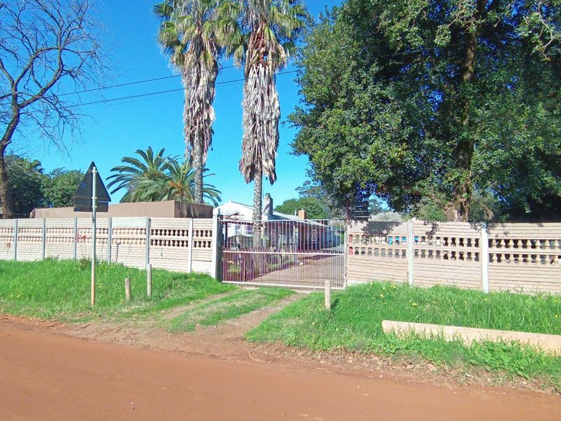 Street view of the property entrance featuring a precast concrete boundary wall and a metal driveway gate.