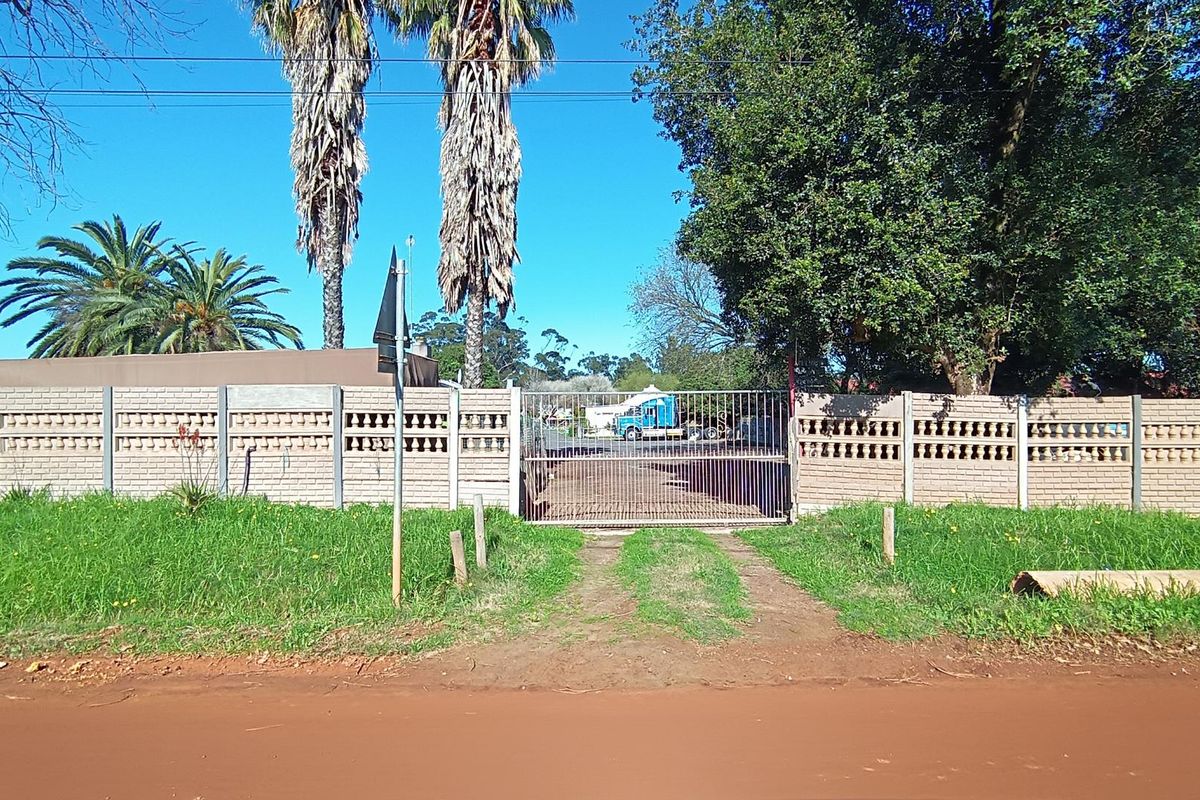 Front view of the property featuring a brick boundary wall and a metal security gate providing access to the driveway.