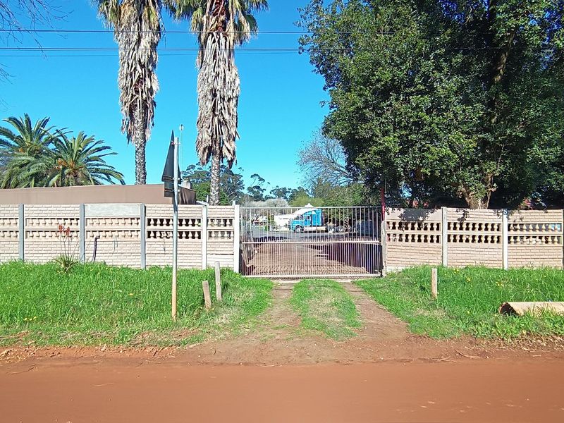Front view of the property featuring a brick boundary wall and a metal security gate providing access to the driveway.