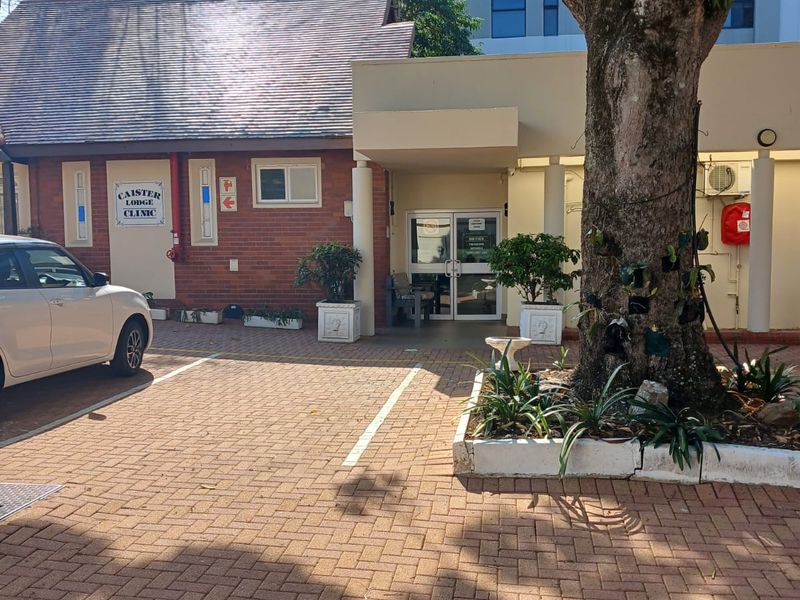 Front exterior view of the Caister Lodge Clinic entrance, featuring brick paving, a covered entryway, and established landscaping.