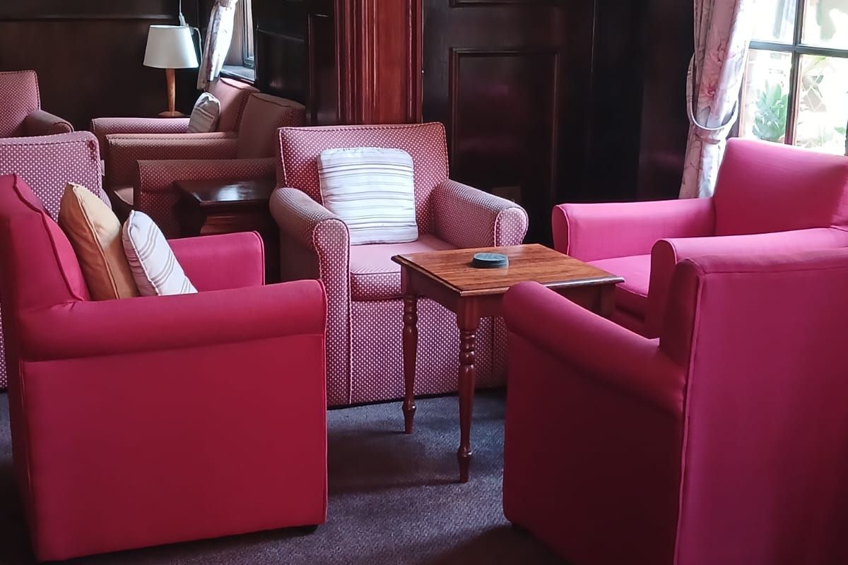 A cozy lounge area featuring dark wood wall paneling, traditional wall sconces, and carpeted flooring, creating a classic, pub-style atmosphere.