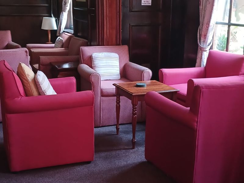 A cozy lounge area featuring dark wood wall paneling, traditional wall sconces, and carpeted flooring, creating a classic, pub-style atmosphere.