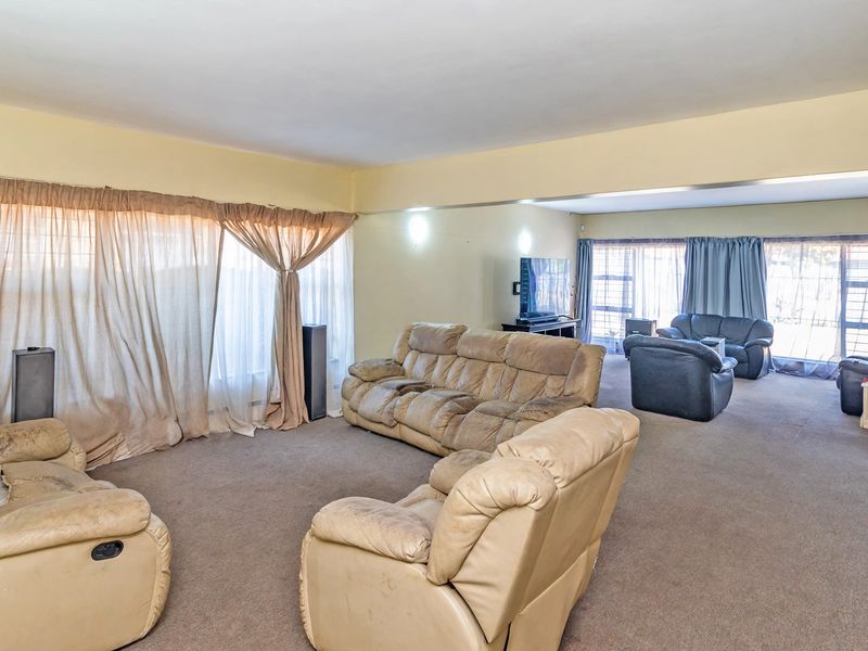 Spacious living area featuring carpet flooring and large windows, offering a versatile layout for comfortable family living.