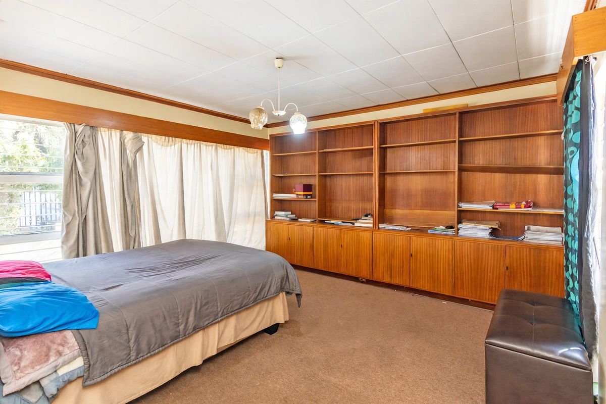 Spacious bedroom featuring extensive built-in wooden shelving and cabinetry, large windows for natural light, and neutral carpeting.