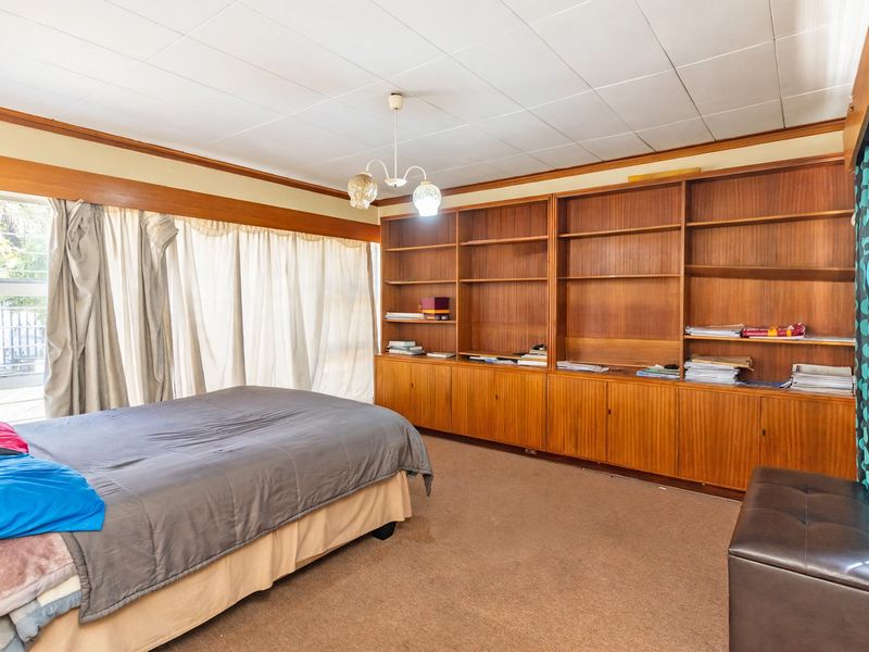 Spacious bedroom featuring extensive built-in wooden shelving and cabinetry, large windows for natural light, and neutral carpeting.