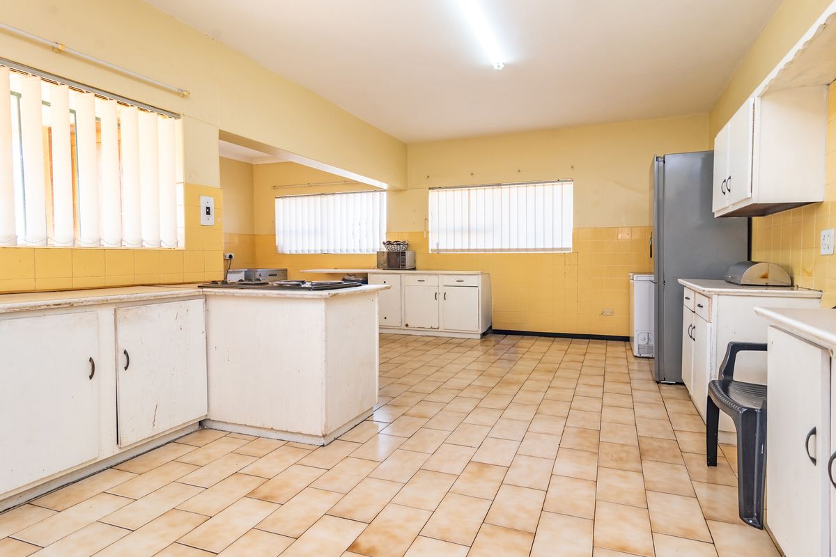 Spacious kitchen featuring built-in cabinetry, tiled flooring, and a built-in hob, offering a functional layout with significant potential for modernization.