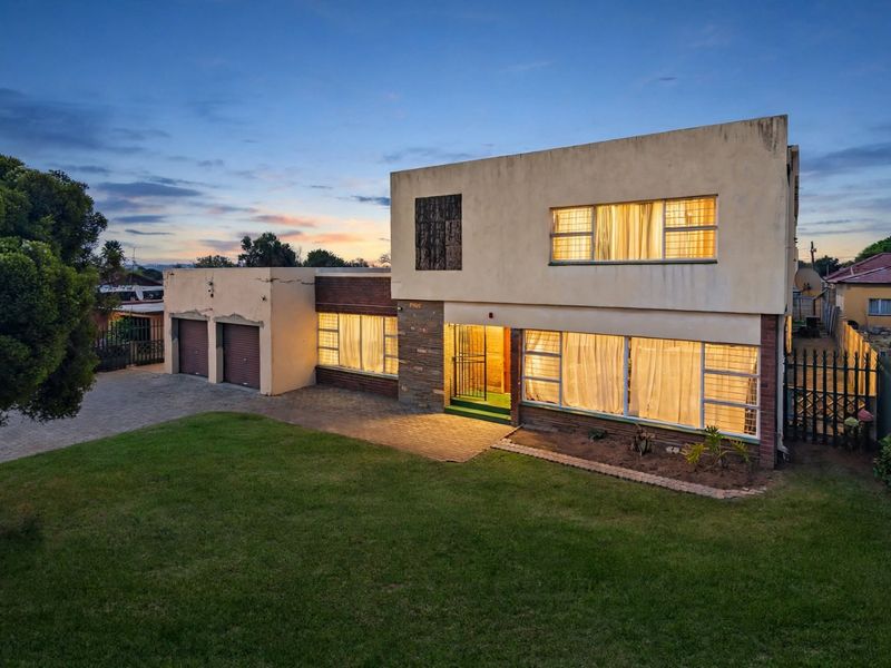Front elevation of a two-story residential house featuring a double garage, paved driveway, and stone cladding accents at dusk.