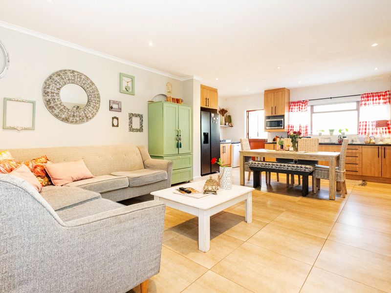 Open-plan living and dining area featuring tiled flooring, recessed lighting, and a functional kitchen with built-in cabinetry and appliances.