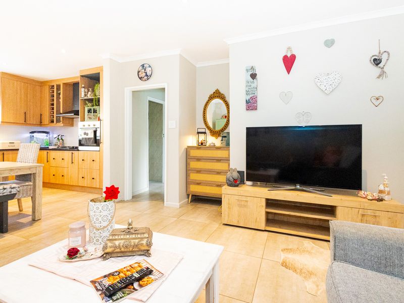 Open-plan living area featuring tiled flooring and a functional kitchen with built-in cabinetry, oven, and extractor fan.