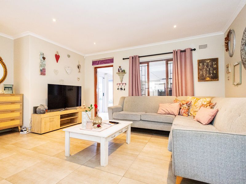 A comfortable living room featuring tiled flooring, recessed downlighting, and a window with security bars, offering a functional and well-maintained space.