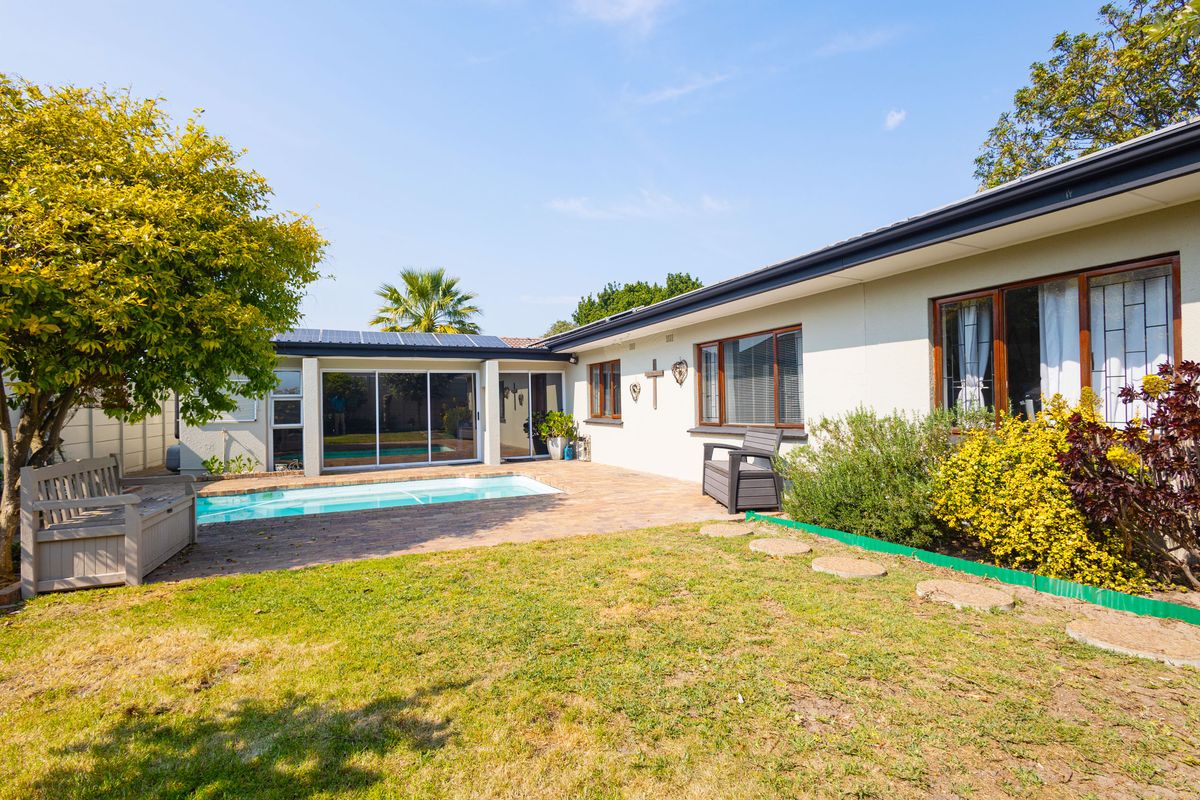 Rear exterior view featuring a swimming pool, paved patio area, and direct access to the home via sliding glass doors.