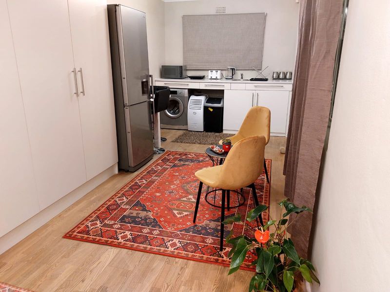 Compact kitchen area featuring white built-in cabinetry, laminate flooring, and integrated storage, providing a functional and efficient space.